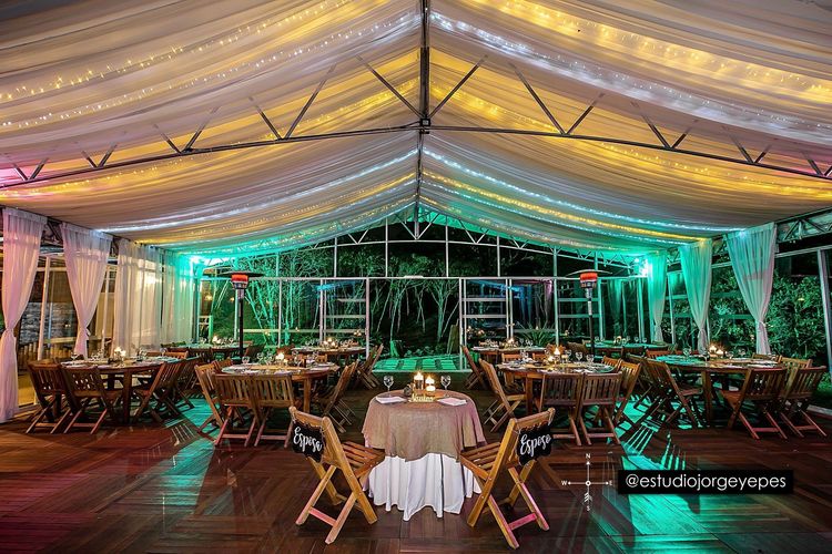 Carpa salón iluminada de noche con las mesas montadas